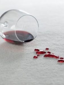 a glass of wine tipped over on a white carpet